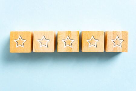 White five stars illustrated on wood blocks toy and blue background. Branding, reputation and feedback concept.の写真素材