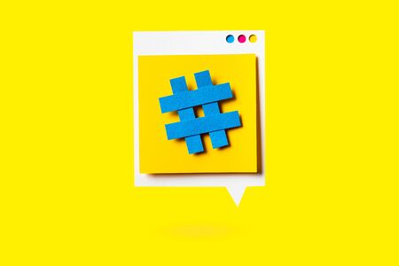 Paper cutout of hashtag symbol on a yellow speech bubble on yellow background. Concept of social media and digital marketing.の写真素材
