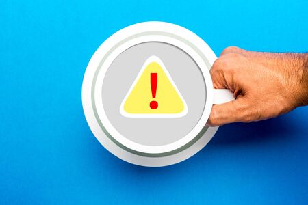 Concept of warning, caution, error, risk, do not open. Exclamation mark illustrated on paper cup and yellow background, with a man holding a cup on blue background.の写真素材