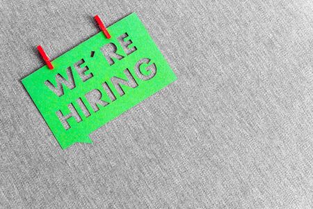 "We're hiring" green banner on grey texture background with space for text. Job vacant and employment concept.の写真素材