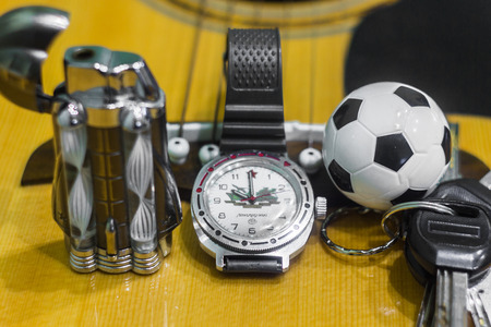 Wrist watch, cigarette, lighter, keychain with keys and acoustic guitar in the backgroundの写真素材