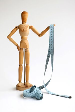 Wooden Dummy Measuring Waist With Blue Measure Tape isolated on a white backgroundの写真素材