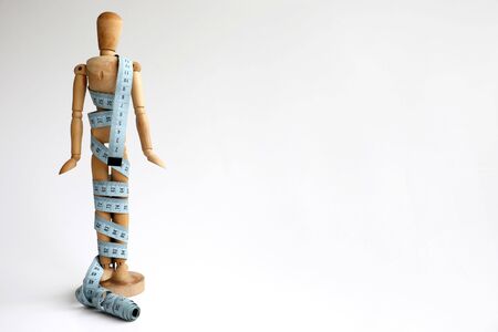Wooden Dummy Measuring Waist With Blue Measure Tape isolated on a white backgroundの写真素材