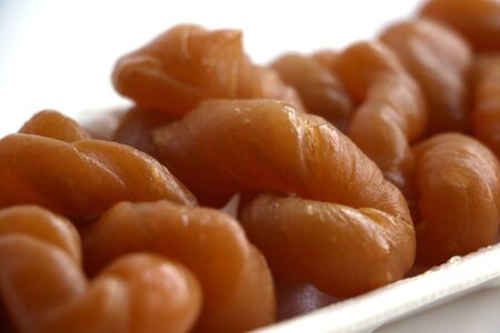 Traditional South African sweet koeksisters covered in syrup, isolated in a polystyrene tray on white backgroundの写真素材