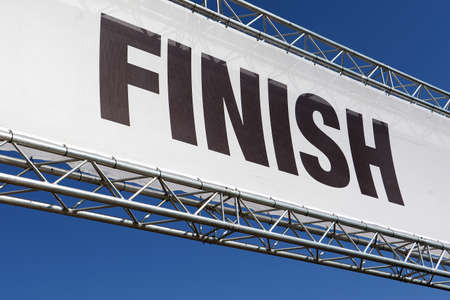 Isolated finish line banner to mark the end of a race against a clear blue summer skyの写真素材