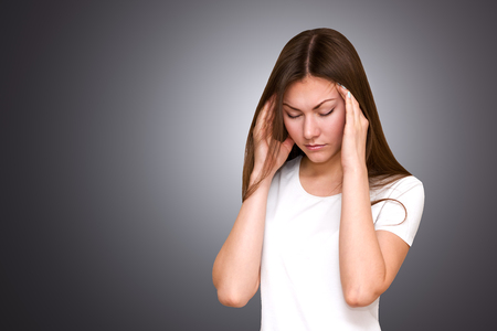 Stress and headache. Young woman having pain. holds his head in his hands.の写真素材