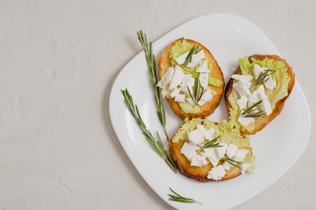 Italian bruschetta with soft cheese, tomatoes and fresh salad on the plate. Space for textの写真素材