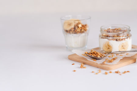 Ingredients for homemade oatmeal granola in glass jar. Oat flakes, honey, raisins and nuts. Healthy breakfast concept with copy space.の写真素材