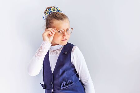 A beautiful little brunette girl looks at the camera trying on glasses. Vision correction. Ophthalmology.の写真素材