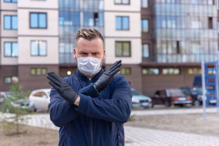 Kovid concept 19. portrait of a Caucasian man on the street showing a hand gesture puts on a protective mask and gloves, prevent the spread of the crown virus.keeping a safe distance.の写真素材