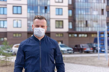 Concept of kovid 19. portrait of a Caucasian man on the street in the city. wearing a medical mask and gloves to prevent the rapid spread of the corona virus.keeping a safe distanceの写真素材