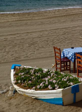 A boat with flowers next to a cafe on a spanish beachの写真素材
