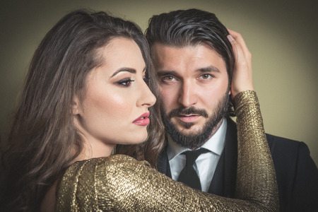 Young blonde woman embracing an elegantly dressed beard man looking straightの写真素材