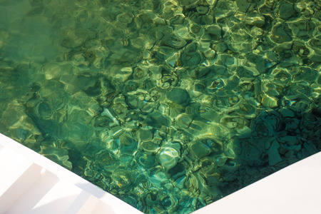 Green, clear ocean water with rocks at the bottom captured in V shape. Concept