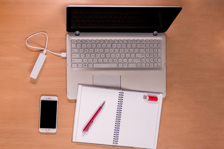 Business daily  technology on the desk: open laptop with charging power bank, mobile phone and open...