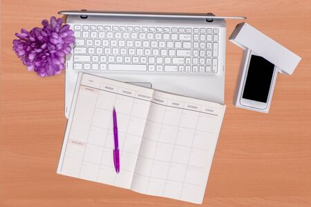 Business daily  technology on desk: open silver laptop, unboxed mobile phone and open notebook with...
