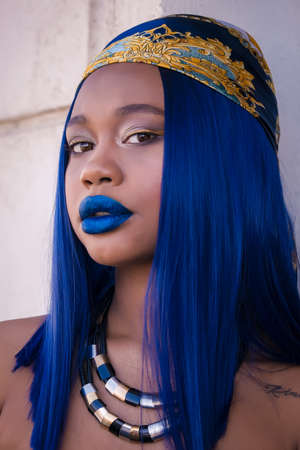 Macro beauty portrait of sensual African woman with electric blue hair and full blue lips, with powerfull expressionの写真素材