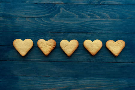 Row of five heart cookies on wooden blue background horizontal photoの写真素材