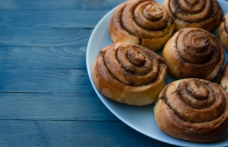 Homemade swirled rosy buns on a blue plate on the right on a blue wooden backgroundの写真素材