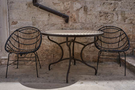 Two chairs and a stylish table on the pale brown background wall in Croatian style. Outdoor patio cafe with empty sitting placeの写真素材