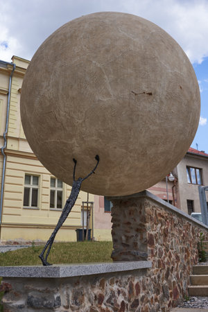 Rakovnik, Czech Republic - July 2, 2022 - the statue of a man rolls a heavy stone up the mountainside on a sunny summer afternoonのeditorial素材