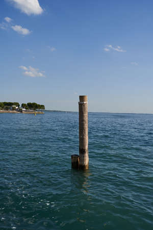 The clear blue water of Lake Garda with wooden stake on a summer afternoonの写真素材