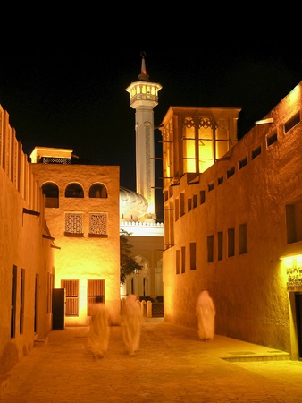 Arab men, in the old merchant quarter of Bastakiya in Dubai, walking to their mosque for evening prayer.の写真素材