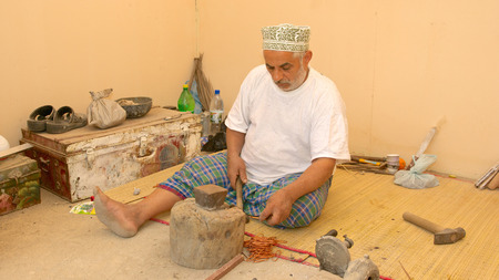 MUSCAT, OMAN - FEBRUARY 1, 2008  A bearded Omani coppersmith, wearing a traditional kuma  cap , at work in Muscat, in the Sultanate of Oman のeditorial素材