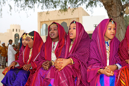Omani girls in traditional dress take a break during a cultural festival in Muscat, in the Sultanate of Oman.のeditorial素材