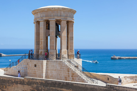 People at Siege Bell Memorial at St Christopher Bastion at Grand Harbor, Valletta, Malta.のeditorial素材