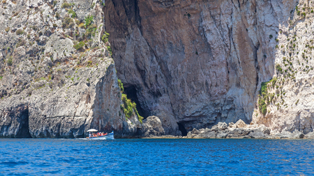 Unidentified tourists in a boat exploring the Blue Grotto coast in the southern part of Malta.のeditorial素材