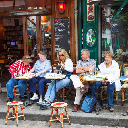 Unidentified patrons relaxing and enjoying a drink at a cafe in Montmartre in Paris.のeditorial素材