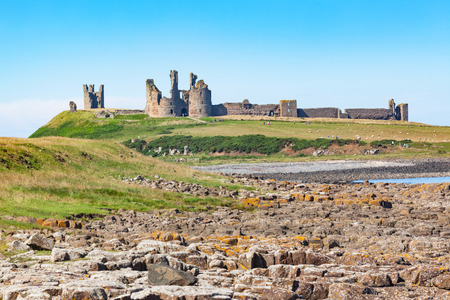 The coast of Northumberland in northern England, between the villages of Craster and Embleton. Dunstanburgh Castle, a 14th-century fortification, can be seen in the background.のeditorial素材