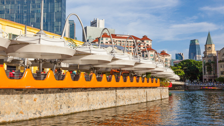 Diners at a colorful restaurant at Clarke Quay on the Singapore River, with skyscrapers in the background.のeditorial素材