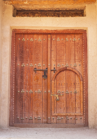 A traditional Arabian 'door within a door' in a building in in Al Ain, in the emirate of Abu Dhabi, United Arab Emirates.の写真素材