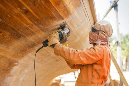 An unidentified workman renovating a traditional wooden dhow at the Dhow Boatyard in Abu Dhabi, United Arab Emirates.のeditorial素材