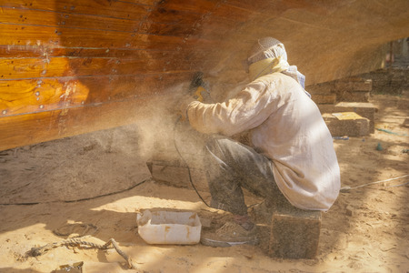 ABU DHABI, UAE - MARCH 27, 2005: An unidentified workman renovating a traditional wooden dhow at the Dhow Boatyard in Abu Dhabi, United Arab Emirates.のeditorial素材