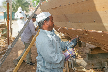 ABU DHABI, UAE - MARCH 27, 2005: An unidentified workman building a traditional wooden dhow at the...