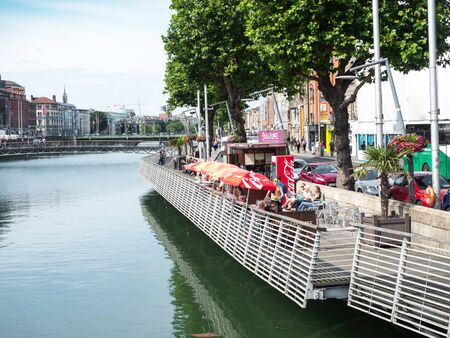 DUBLIN, IRELAND - AUGUST 1, 2019: People at an outdoor cafe next to the River Liffey, Dublin,  Ireland.のeditorial素材