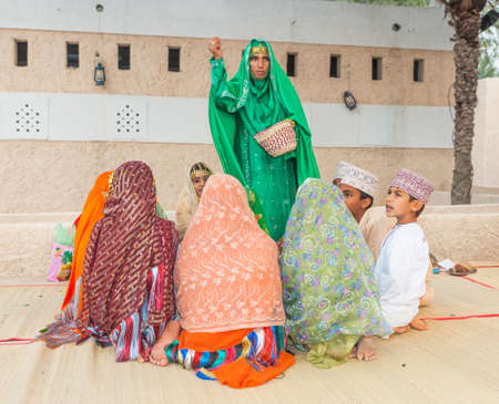 MUSCAT, OMAN - FEBRUARY 1, 2008: An Omani teacher in traditional dress giving an outdoor class to her young pupils.のeditorial素材