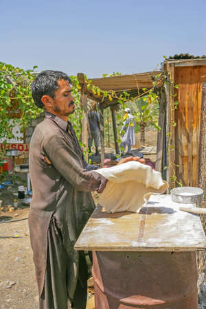 MARBAD, UAE - SEPTEMBER 28, 2005: A farm labourer making bread outdoors in a remote area near Marbad in the emirate of Fujairah in the United Arab Emirates.のeditorial素材
