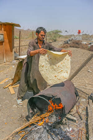 MARBAD, UAE - SEPTEMBER 28, 2005: A farm labourer making bread outdoors in a remote area near Marbad in the emirate of Fujairah in the United Arab Emirates.のeditorial素材