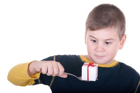 Boy looks at a spoon with a gift on a white backgroundの写真素材