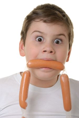 Surprised boy holds sausage in mouth isolated in whiteの写真素材