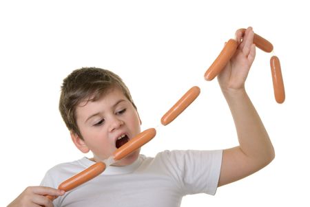 Hungry boy bites sausage isolated in whiteの写真素材