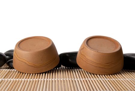 Two turned clay cups, mat and stones isolated in whiteの写真素材