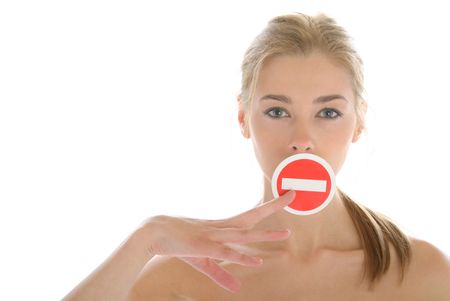 Woman holds prohibiting sign before mouth isolated in whiteの写真素材