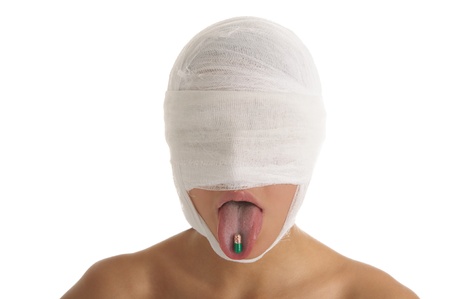 Woman with bandaged head with tablet in tongueの写真素材