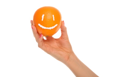 Hand holds orange with drawn smileの写真素材