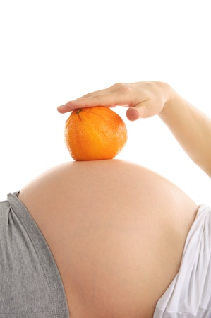 Pregnant woman's abdomen with orangeの写真素材